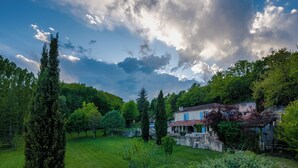 A large, open grassy area with a stone wall and a building with blue windows and a red roof. - Lacoume Saint Jacques (Auch)