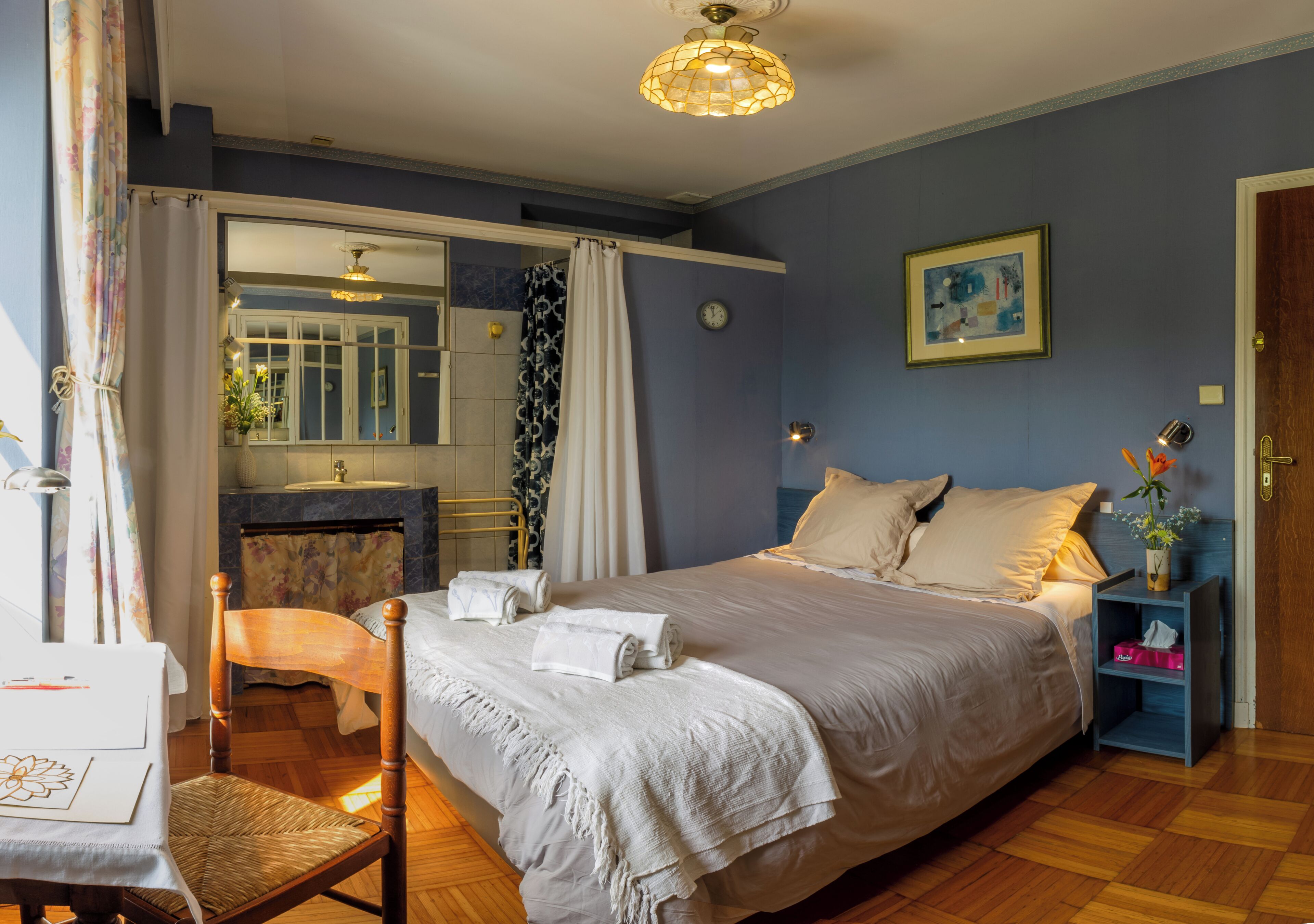 Een keurig opgemaakt slaapkamer met een bed, een stoel, een tafel en een nachtkastje.
