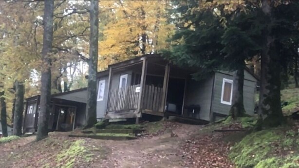 Eine Hütte mit Veranda, umgeben von Bäumen im Herbstlaub.