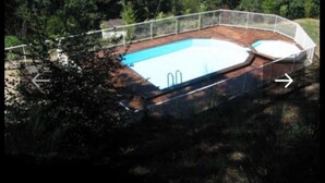 Ein Schwimmbad mit Holzterrasse und Metallzaun.