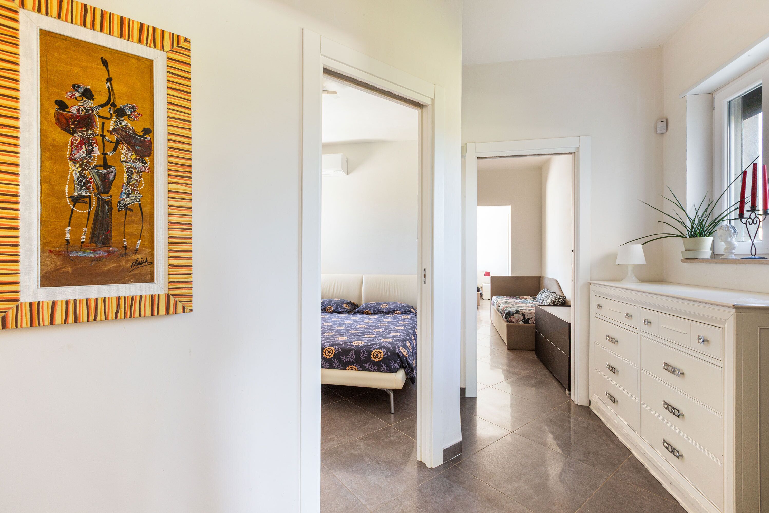 A hotel room with a bed, a dresser, a mirror, and a painting on the wall.