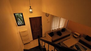 A staircase leading to a living area with a sofa and a small table. - 5 Min to Benaulim Beach SERENE ESCAPE VILLA (Benaulim)