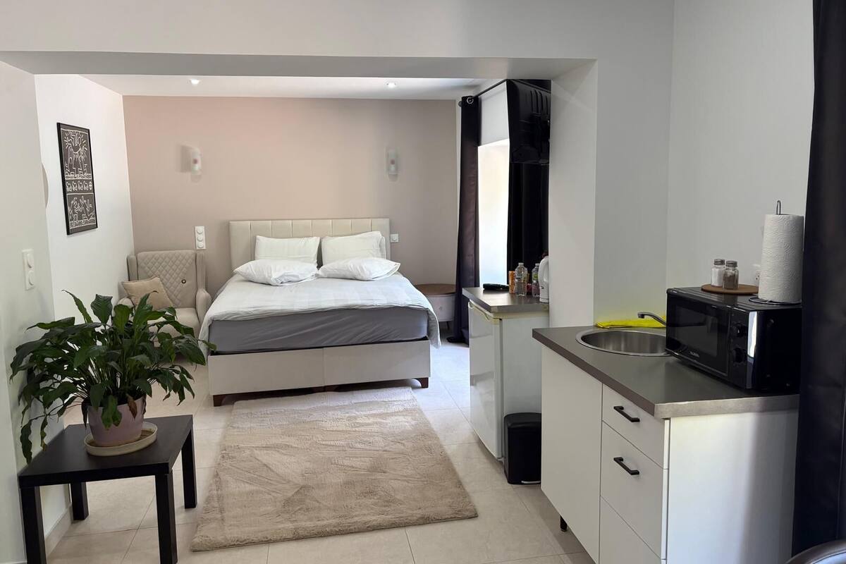 Een slaapkamer met een bed, nachtkastje en een bloempot.