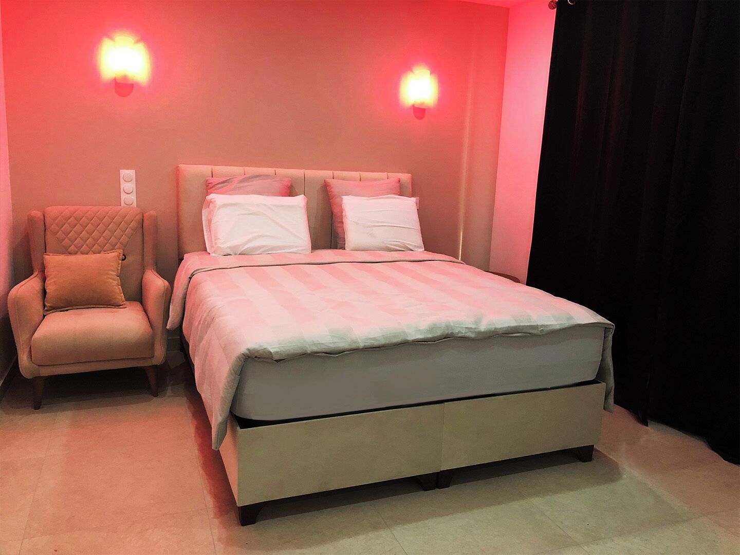 A bedroom with a bed, a chair, and two wall-mounted lights.
