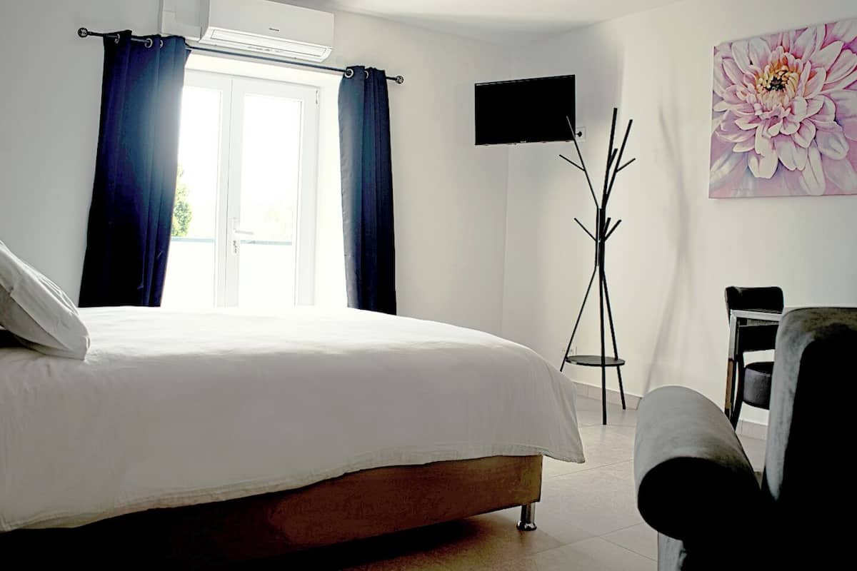 Een slaapkamer met een bed, een aan de muur bevestigde televisie en een vloerlamp.