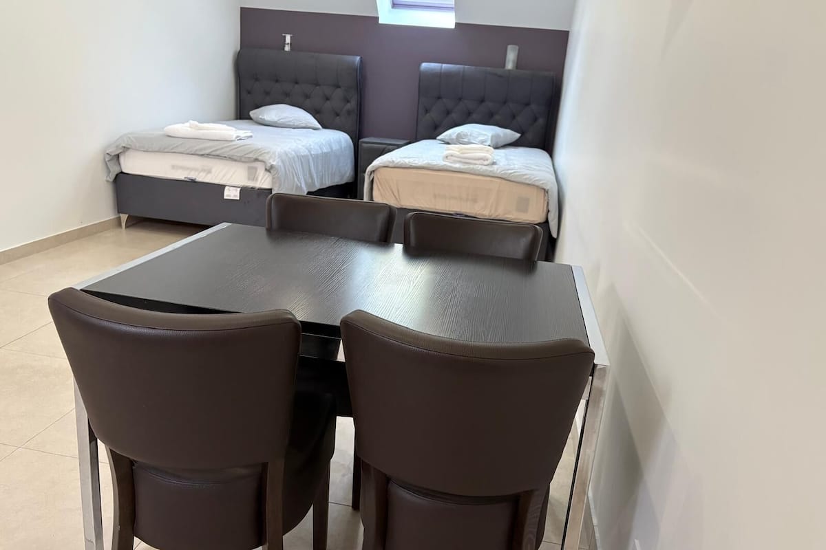 Een kamer met twee bedden, een tafel en vier stoelen.