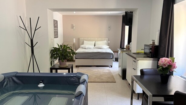 Una camera d'albergo moderna con un letto, un angolo cottura, un'area pranzo e una vasca da bagno.