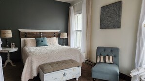 A bedroom with a bed, bedside tables, a chair, and a window with curtains. - Experience a 12-room historic home on Lake Manistique with your own private chef (Curtis)
