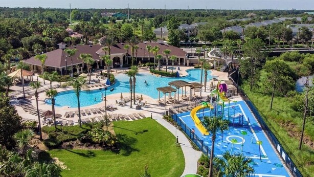 A resort with multiple swimming pools, a water slide, and lounge areas surrounded by palm trees and greenery. - Movie Theater/Game Room, FREE Pool Heat! No Rear Neighbors, Minutes to Disney! (Kissimmee)