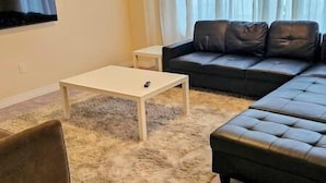 A living room with a white coffee table, a black leather sofa, and a fluffy rug. - Luxury 5BD 4BR Sleep 12 - Large Groups, Family, Events , Wedding near Brantford (Brant)