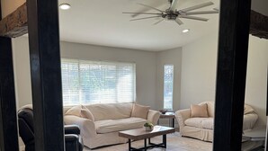 Un salon spacieux avec deux canapés de couleur beige, une table basse et un ventilateur de plafond.