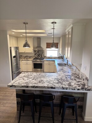 A kitchen with a granite countertop, stainless steel appliances, and pendant lighting. - Large Groups 4-Bedroom, 2-Bath Paso Robles Retreat on Eastside Near Top Wineries (Paso Robles)