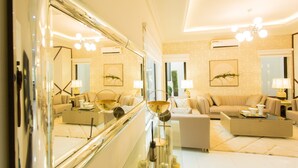 A spacious living room with a large mirror, a sofa, a coffee table, and a chandelier.