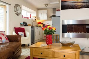 Een knus woongedeelte met een kitchenette, een eethoek en een zithoek met een bank en salontafel.