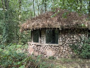 Une cabane rustique avec un toit de chaume, des murs en pierre et une fenêtre.