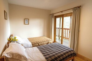 Une chambre avec deux lits, un plancher en bois, une fenêtre avec des rideaux et un tableau au mur.