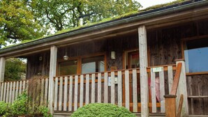 A rustic wooden cabin with a porch, windows, and a small garden. - Robin's Perch Eco Lodge Apartment, Lampeter (Lampeter)