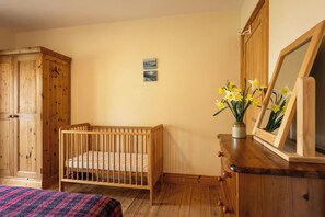 A room with a wooden crib, a dresser with a mirror, and a small painting on the wall. - Robin's Perch Eco Lodge Apartment, Lampeter (Lampeter)
