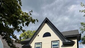 A two-story house with a gabled roof, large windows, and a front porch. - Just remodeled, for you! (Grand Rapids)