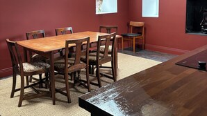 Ein Essbereich mit Holztisch und Stühlen, einem Teppich, einem Oberlicht und einem an der Wand befestigten Fernseher.