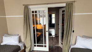 Une chambre avec deux lits simples, un tapis à motifs et une porte donnant sur une autre pièce.
