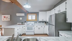 Una cocina moderna con armarios blancos, un refrigerador de acero inoxidable, una estufa blanca y una encimera de mármol.