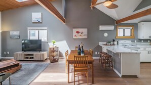 Una cocina amplia con una isla central, una mesa de comedor de madera y sillas. Hay un ventanal que proporciona luz natural y un ventilador de techo sobre la isla.