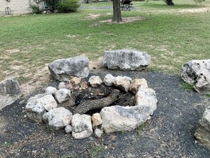 A fire pit surrounded by large rocks in a grassy area. - Charming 2-bedroom cabin right on the Frio River - Cabin #1 (Concan)