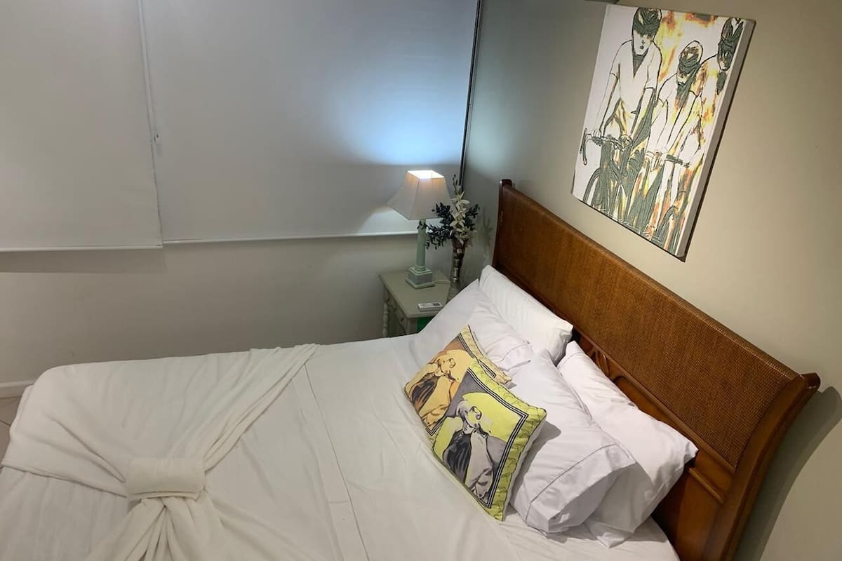 Uma cama bem arrumada com lençóis brancos e um travesseiro com um personagem de desenho animado.