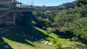 A building with a covered walkway and a view of a lush green landscape. - Casa 24 Búzios (Buzios)