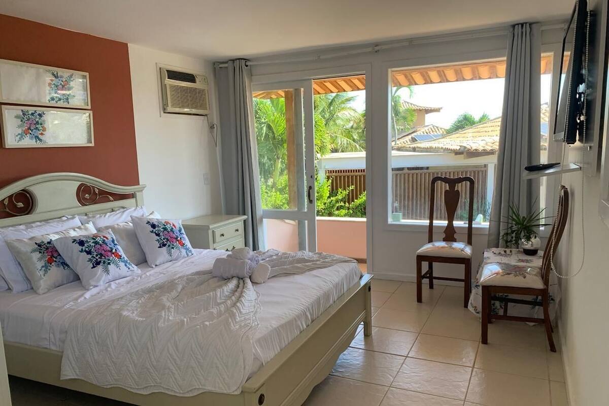 Quarto com cama, uma cadeira, uma mesa e vista para o exterior.