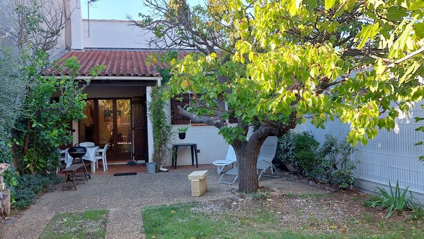 A patio area with a table and chairs, a barbecue grill, and a tree.