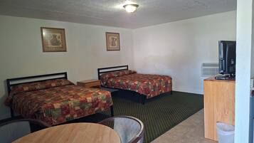 A hotel room with two beds, a desk with a computer, a television, and a small table.