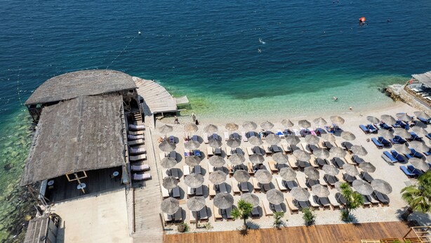 A beachside resort with a wooden deck, lounge chairs, and umbrellas.