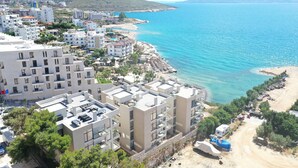 A coastal town with modern buildings, a beach, and a clear view of the sea.