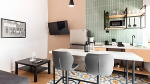 A modern kitchen with a large island, two bar stools, a flat-screen TV, and a coffee machine. - Casona 212 | Style, Connectivity & Parking (Unknown)