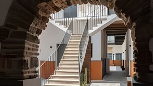A modern interior with a central staircase, stone archway, and a view into another room. - Casona 212 | Style, Connectivity & Parking (Unknown)