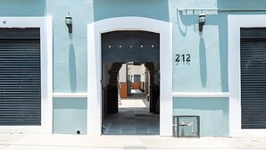 A building entrance with a number '212' above the door, a covered walkway, and a small window with a metal grate. - Casona 212 | Style, Connectivity & Parking (Unknown)