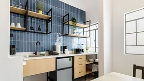 Una cocina moderna con lavavajillas integrado, un fregadero y una ventana sobre la encimera. Hay estantes de madera con plantas y utensilios de cocina.