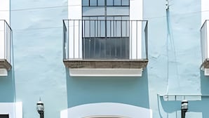 Un edificio con fachada azul claro, un balcón y el número “212” en el lado derecho.