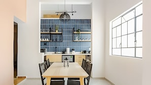 Una cocina moderna con salpicadero azul, armarios de madera y un comedor con mesa y sillas.