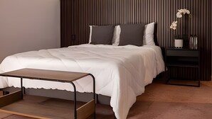 Un dormitorio moderno con cama, mesita de noche y un pequeño banco.