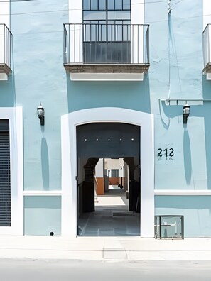 A building with a light blue facade, a balcony, and a number "212" on the right side.