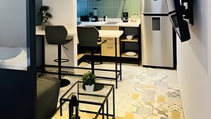 A compact kitchen with modern appliances, a dining area with two chairs, and a small table with a plant. - Casona 212 |Luxury Loft in Puebla Centro + Parking (Heroica Puebla de Zaragoza)