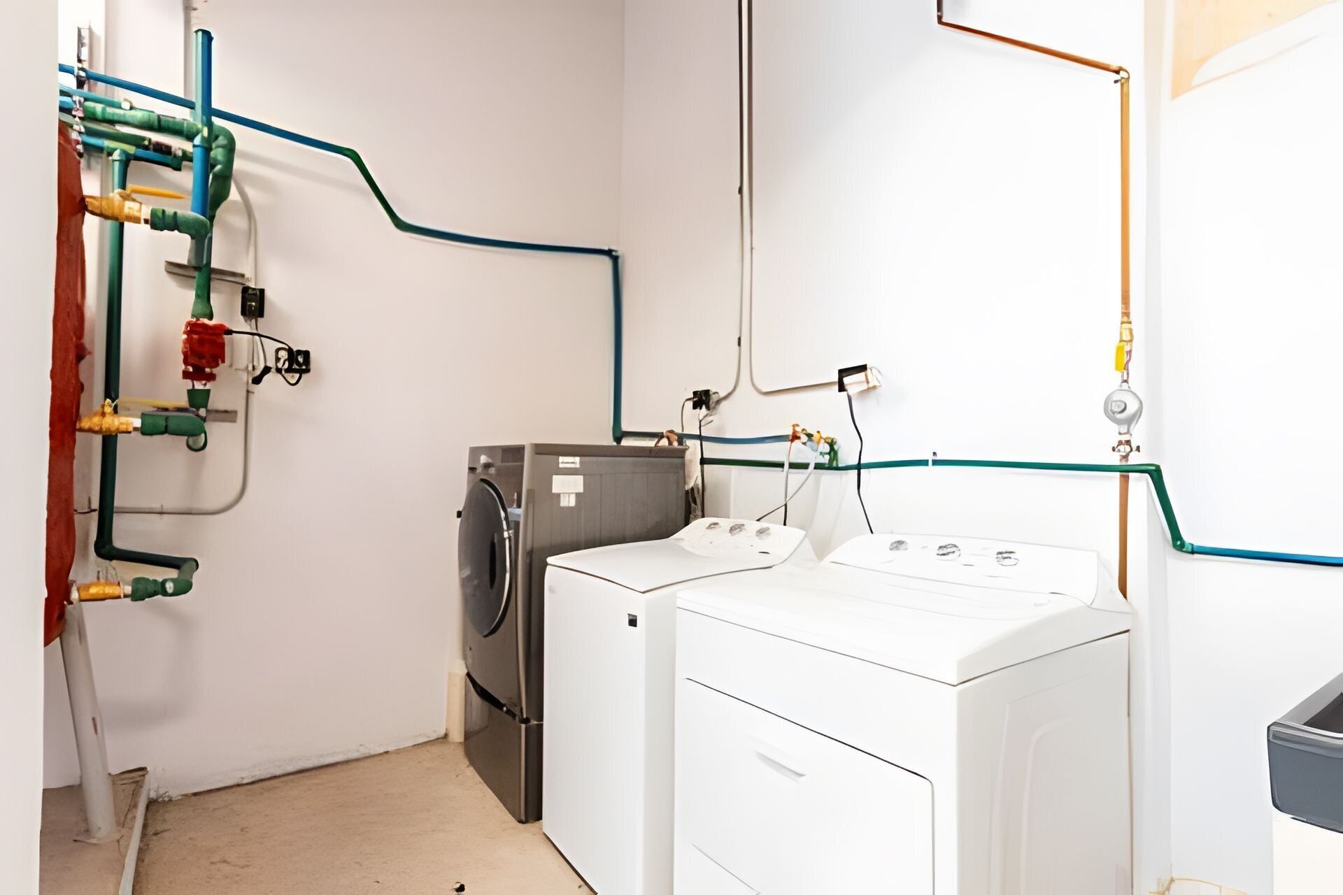A laundry room with two washing machines, a dryer, and visible plumbing.