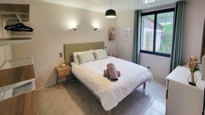 A bedroom with a bed, bedside tables, a dresser, a hanging rack, and a window with a view of greenery. - Charming cottage with pool, air-Con, views & high speed WiFi (La Sauvetat-du-Dropt)