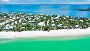 Eine Luftaufnahme eines Küstenwohngebiets mit Häusern, einem Strand und klarem, blauem Wasser.