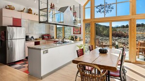 A modern kitchen with a central island, large windows, and a dining area with wooden furniture. - 25 Acre Artist Ranch, hot tub & tennis, near Aspen (Carbondale)