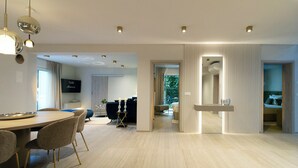 Ein modernes Wohnzimmer mit Essbereich, einem Fernseher und Blick ins Freie.