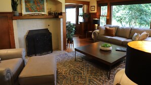 Una sala de estar con chimenea, un sofá, una mesita de centro y una alfombra estampada.